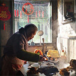 A photo of an old woman cooking in her kitchen