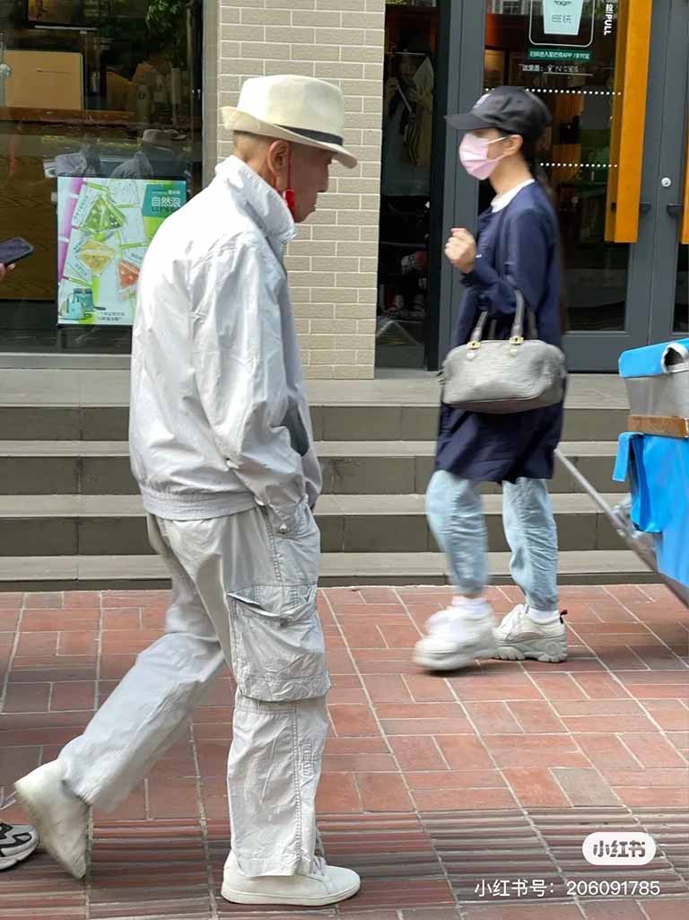 An elderly Chinese gentleman wearing a white suite and hat