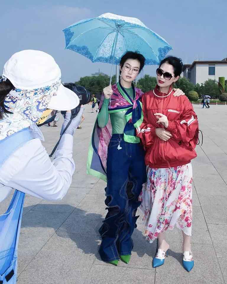 Two Chinese ladies posing for a photograph under an umbrella