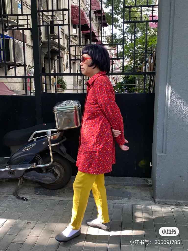 An elderly Chinese man taking a walk in a bright outfit