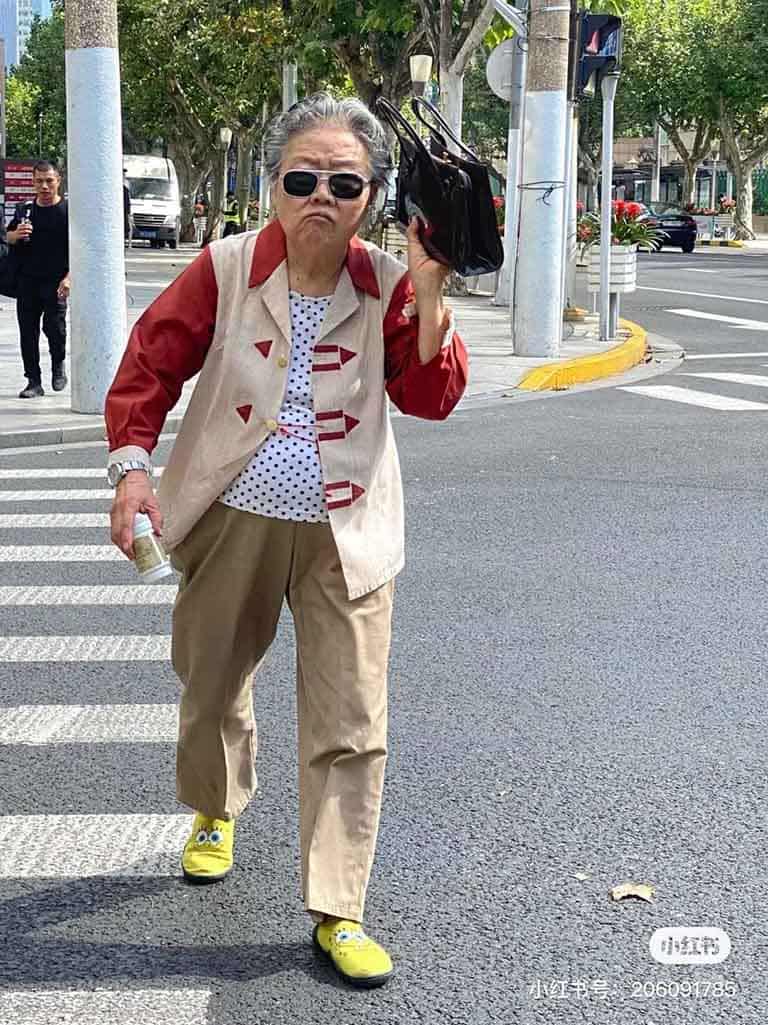 An elderly Chinese citizen walking across a road