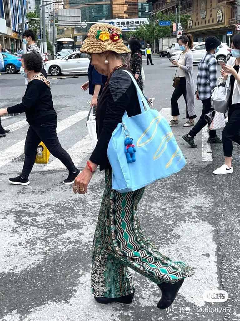 An elderly Chinese lady carrying a brightly coloured bag