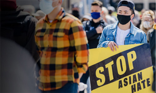 Man at demonstration with 'Stop Asian Hate' banner